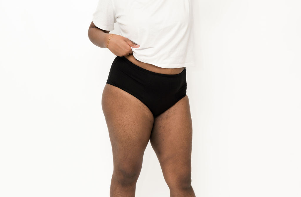 Person wearing black high-waisted Brolly underwear and a white t-shirt on a white background - Black