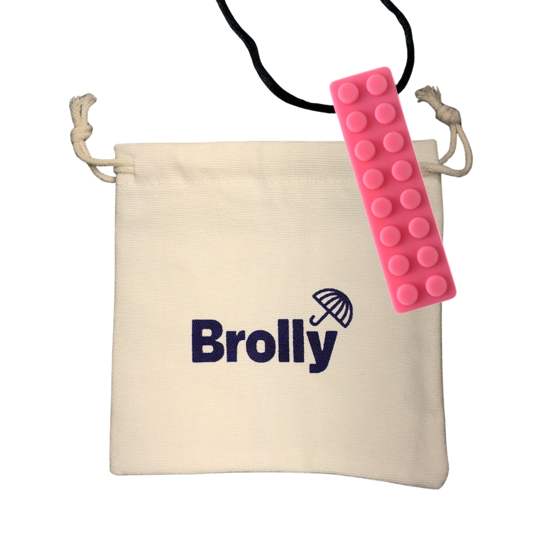 Beige drawstring pouch and Pink brick-shaped Brolly Chew Necklace on a black cord against a white background