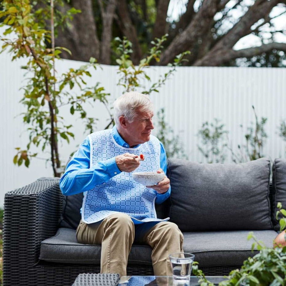Elderly man wearing blue square pattern eating outdoor