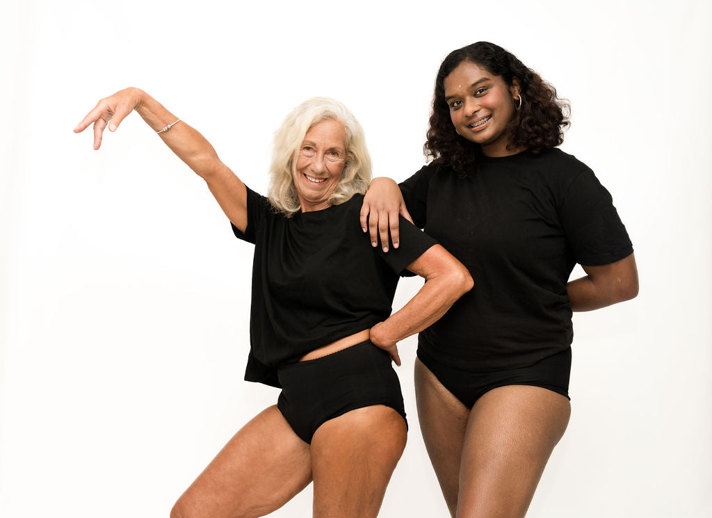 Two women standing side by side, each wearing Brolly Sheets full brief absorbent underwear, shown in a neutral, everyday setting to highlight fit, comfort, and discreet coverage.