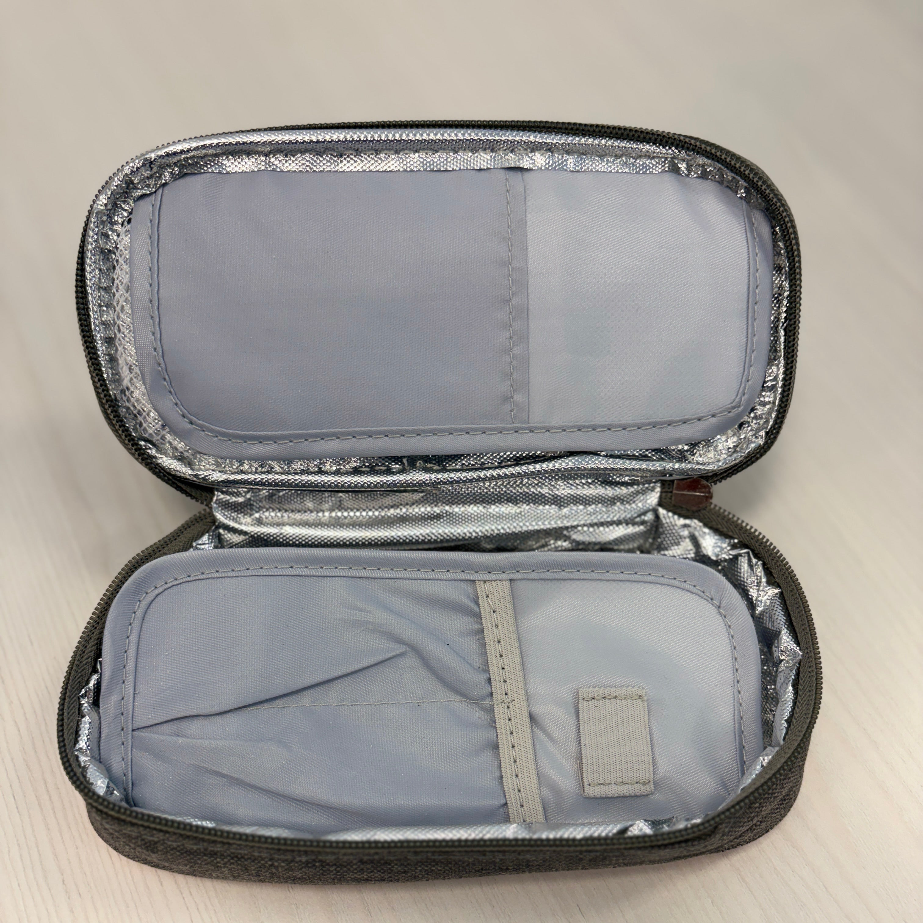 Open gray Medicine Cooler Bag on a light wooden surface

